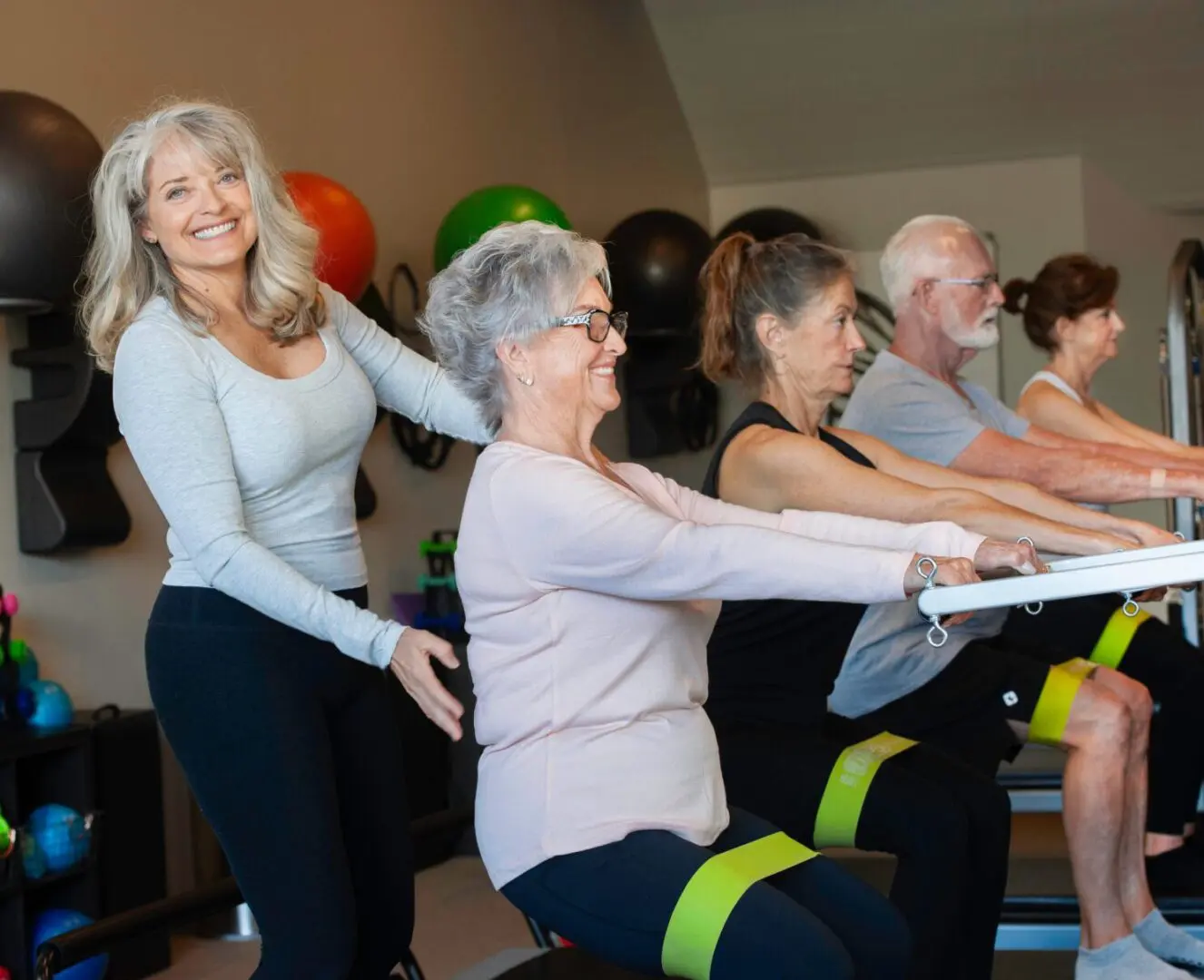 A fitness instructor guides seniors through a seated exercise class.